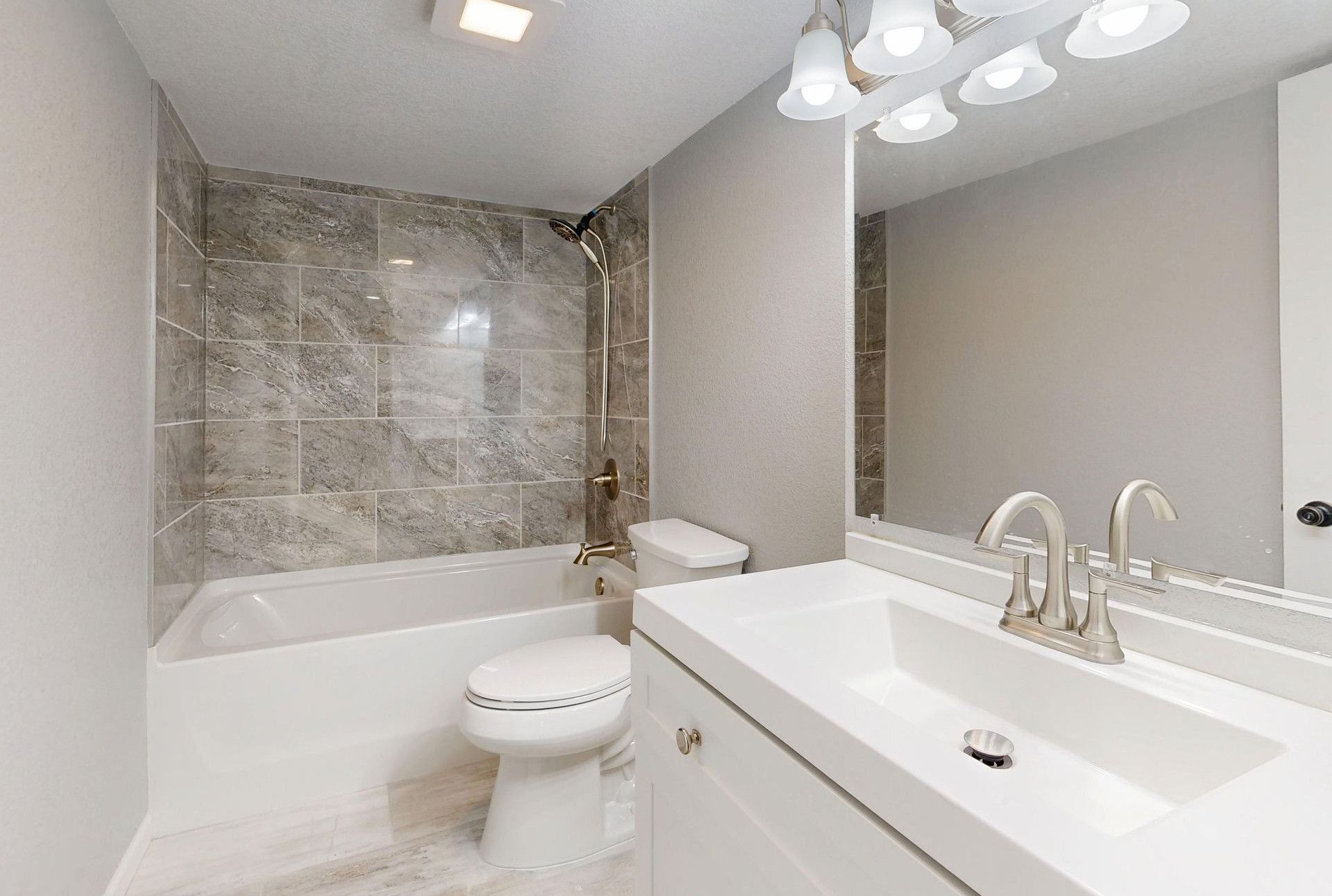 Elegant modern bathroom featuring marble tiles and sleek white vanity.